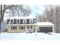 Beige two-story house with dark brown garage door, snow covered yard, and mature trees at 9114 Rymark Dr, Indianapolis, IN 46250