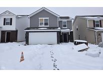 Two story house with white garage door and snow covered yard at 11027 Walter Dr, Indianapolis, IN 46235