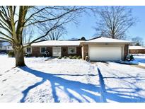 Brick ranch home with attached garage, snow-covered yard, and mature tree at 1619 Beech Cir, Plainfield, IN 46168