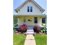 Charming two-story home with inviting front porch adorned with lush red roses and greenery at 325 S Market St, Thorntown, IN 46071