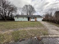 Ranch-style home with green exterior, attached garage, and a yard at 4219 E 43Rd Ct, Indianapolis, IN 46226