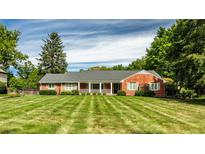 Brick ranch house with a large front yard and mature trees at 500 W 93Rd St, Indianapolis, IN 46260