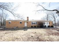 Charming brick ranch home featuring a front yard, chimney, and a welcoming white front door at 7201 E 71St St, Indianapolis, IN 46256