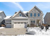 Two-story home with stone accents and three-car garage, snow covered landscaping at 2787 W High Grove Cir, Zionsville, IN 46077