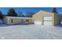 A charming, light-yellow house with a large garage, snow-covered landscape and blue sky at 4870 Little Hurricane Rd, Martinsville, IN 46151