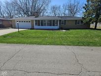 Well-maintained home features a green lawn, attached garage, and sunroom at 515 Wedgewood Dr, Anderson, IN 46013