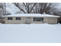Tan ranch house with snow covered lawn and attached garage at 7536 N Sherman Dr, Indianapolis, IN 46240