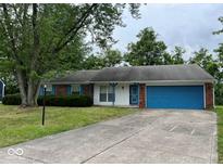 Brick ranch house with a blue garage door and mature trees at 10915 Cherry Lake Pl, Indianapolis, IN 46235