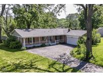 Charming single-story brick home featuring a covered front porch, attached garage, and a spacious front lawn at 475 Golf Ln, Indianapolis, IN 46260