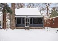 Cute ranch home with screened porch, freshly painted exterior and snow covered yard at 6005 Ralston Ave, Indianapolis, IN 46220
