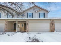 Charming townhouse with a two-car garage, brick accents, and snow-covered landscaping at 7218 Forrester Ln, Indianapolis, IN 46217