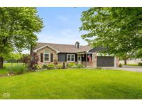 Charming exterior view of home with brick accents, manicured lawn, and an attached two-car garage at 7775 N Kitchen Rd, Mooresville, IN 46158