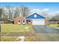 Charming brick home with a blue accent, attached garage, and driveway at 7817 Dartmouth Rd, Indianapolis, IN 46260