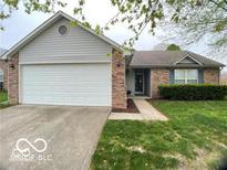 Brick ranch home with attached garage and landscaped lawn at 825 Queensgate Dr, Greenwood, IN 46143