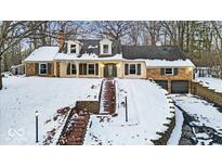 Brick home with snow covered landscaping and a large driveway at 9210 Briarclift Rd, Indianapolis, IN 46256