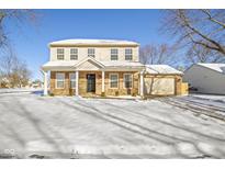 Two-story house with brick and beige siding, covered porch, and attached garage at 10322 Buell Ct, Avon, IN 46123