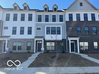 View of new townhomes with brick and vinyl exteriors, front lawns and sidewalks at 10948 Hanovarian St, Zionsville, IN 46077