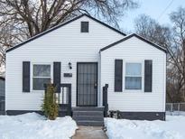 White house with black shutters, gray door, and snowy yard at 3501 Caroline Ave, Indianapolis, IN 46218