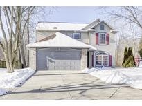 Two-story house with gray siding, red shutters, and a gray garage door, covered in snow at 5334 Thrasher Dr, Indianapolis, IN 46254
