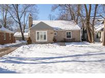 Charming stone ranch house with snowy front yard and landscaping at 5738 Norwaldo Ave, Indianapolis, IN 46220