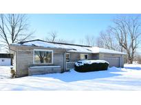 Stone front exterior of ranch home with attached garage, snowy yard, and landscaping at 67 W Brookville Rd, Fountaintown, IN 46130