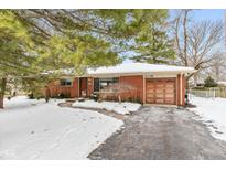 Brick ranch house with attached garage, snow-covered yard, and mature trees at 1119 E Cragmont Dr, Indianapolis, IN 46227