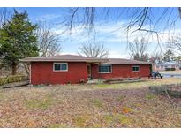Cozy brick home featuring a well-maintained lawn and mature trees providing ample shade at 7020 Pershing Rd, Indianapolis, IN 46268