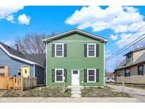 Charming two-story home featuring bright green siding, a white door, and black shutters at 1446 E Naomi St, Indianapolis, IN 46203