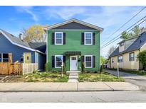 Charming two-story home featuring a vibrant green exterior with black shutters and a well-maintained front yard at 1446 E Naomi St, Indianapolis, IN 46203