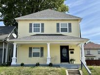 Charming yellow two-story house with a front porch and landscaping at 2705 Shriver Ave, Indianapolis, IN 46208