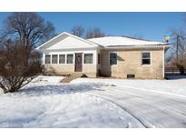 Ranch home with stone and wood siding, snowy yard, and driveway at 502 E Pearl St, Trafalgar, IN 46181