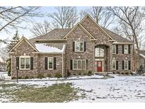 Brick two-story house with a red door, snow-covered lawn, and black shutters at 14446 Stephanie St, Carmel, IN 46033