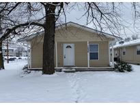Tan house exterior with white door, covered porch, and snowy yard at 1608 Edgecombe Ave, Indianapolis, IN 46227