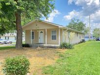 Charming tan single-story home with a cozy front porch and well-maintained landscaping on a sunny day at 1608 Edgecombe Ave, Indianapolis, IN 46227