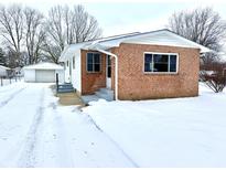 Brick ranch home with snow-covered yard and attached garage at 176 Monroe St, Indianapolis, IN 46229
