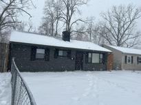 Gray house with black shutters, snowy yard, and chain link fence at 4715 E 33Rd St, Indianapolis, IN 46218