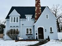 Charming blue home with a brick chimney and snow-covered landscaping at 1203 W 8Th St, Anderson, IN 46016