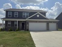 Two-story home boasts gray siding and a brick facade, complemented by a spacious, two-car garage at 251 Dyson Dr, Whiteland, IN 46184