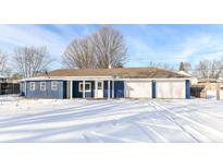 Ranch home with blue exterior, white garage, and snowy yard at 328 Elva St, Anderson, IN 46013