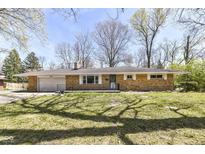 Charming single-story brick home with attached garage, front porch and mature trees and landscaping at 3375 Lincoln Rd, Indianapolis, IN 46222