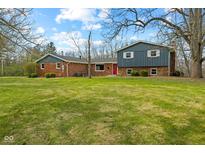 Charming brick home with blue siding, a bright red front door, and a spacious front lawn at 8810 W Tulip Tree Dr, Muncie, IN 47304