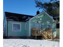 Charming light green house with wood deck and snowy front yard at 135 S 11Th Ave, Beech Grove, IN 46107