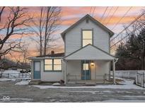 Two-story white house with front porch, snowy yard, and fence at 4702 Michigan Rd, Indianapolis, IN 46228