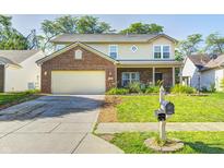 Charming two-story home featuring a brick facade, attached garage, and well-manicured lawn at 7129 Dublin Ln, Indianapolis, IN 46239