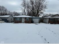 Brick ranch home with attached garage and snow-covered yard at 835 E Berwyn St, Indianapolis, IN 46203