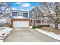 Two-story home with brick and gray siding, white garage door, and landscaping at 10767 Red Pine Dr, Fishers, IN 46037