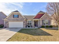 Charming brick home featuring a two-car garage, manicured lawn, and inviting front porch at 15759 Hargray Dr, Noblesville, IN 46062