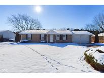 Ranch home with snow covered yard, attached garage, and mature trees at 2511 Ritter Dr, Anderson, IN 46012