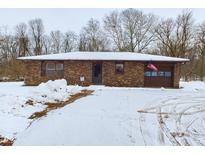 Brick ranch home with attached garage, American flag, and snowy yard at 2584 W Mercer Ln, Pendleton, IN 46064