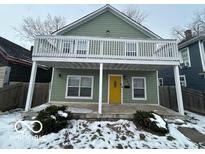 Charming two-story home with a yellow door and balcony at 334 Hamilton Ave, Indianapolis, IN 46201